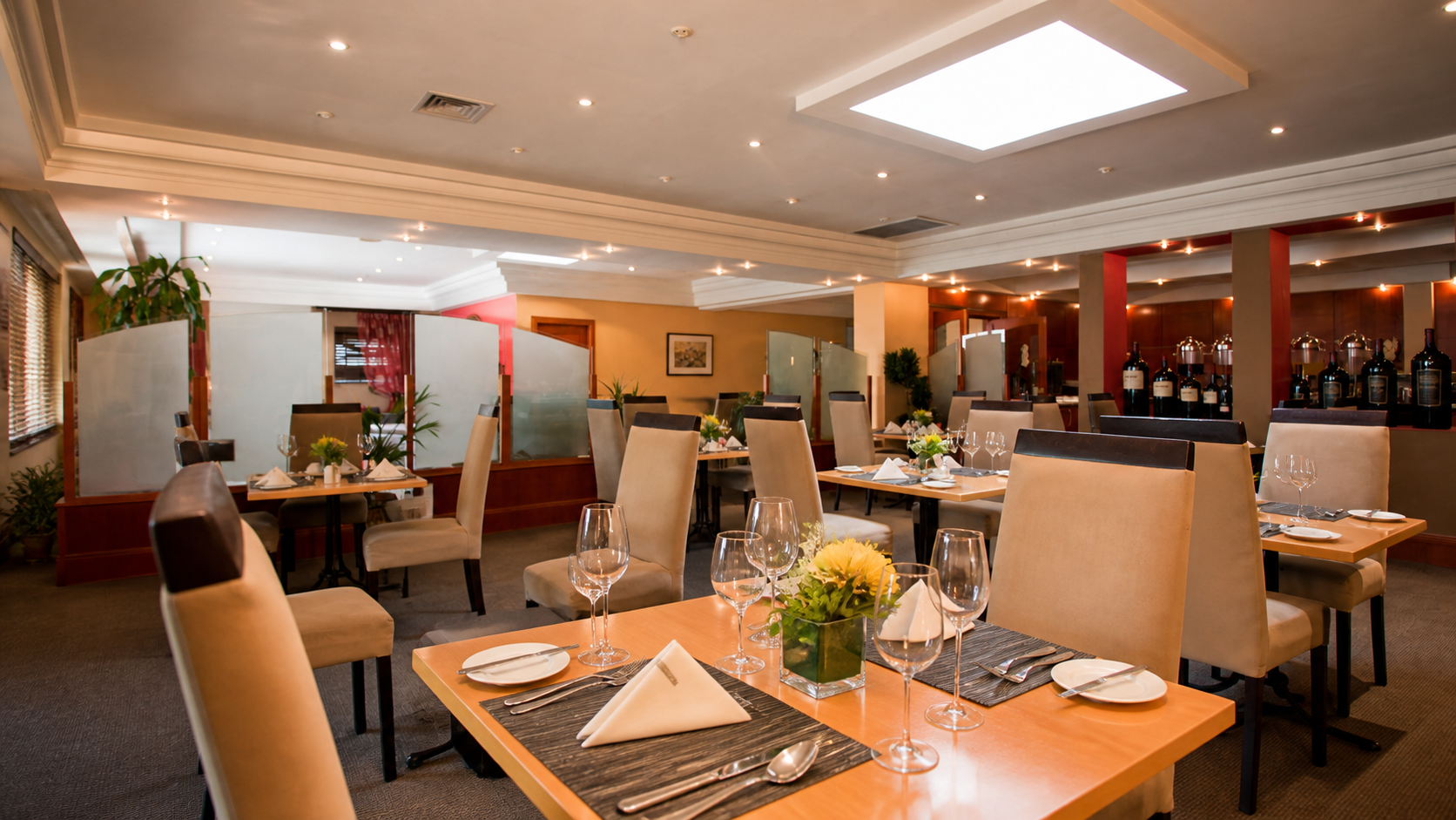 Warmly lit dining room with linen-set tables and beige chairs